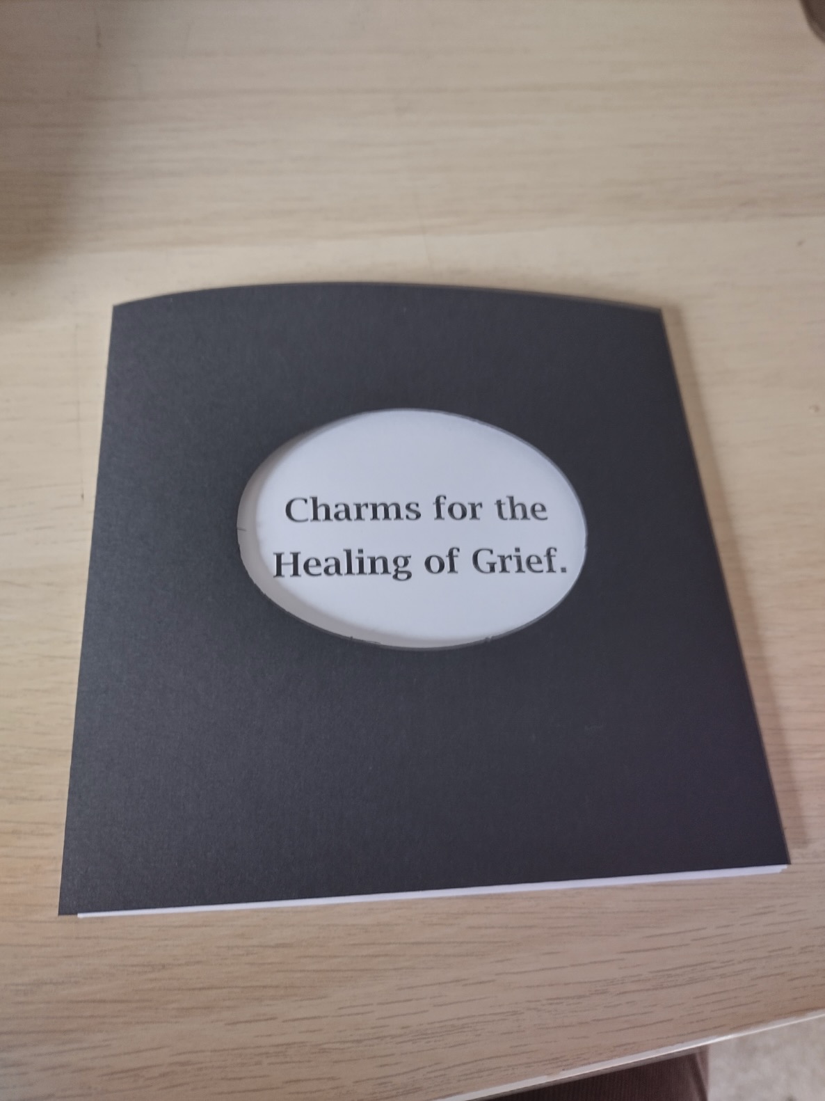 cover of pamphlet, black with cutout, the title is Charms for the Healing of Grief