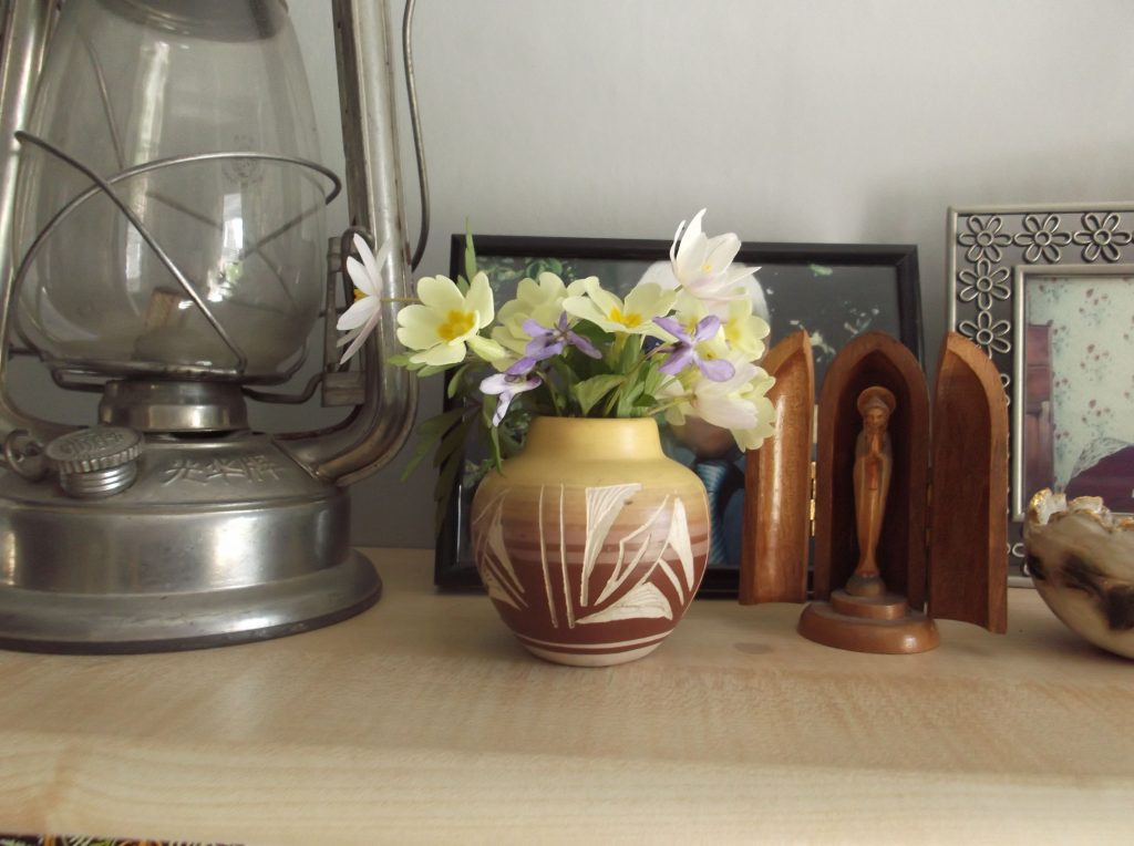 shelf with hurricane lamp vase of flowers and statue