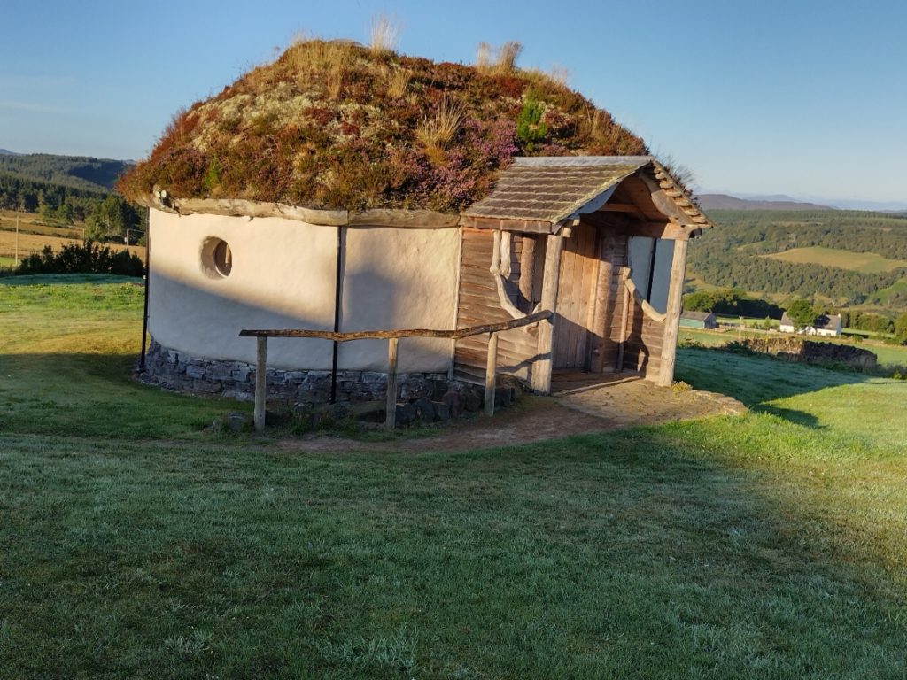 hobbit house, hay bale building with wooden porch and green roof